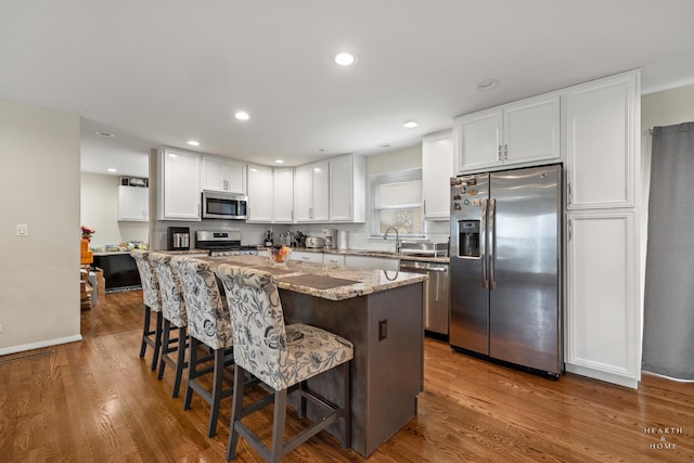 914 W Lynnwood Ave, Arlington Heights, IL 60004 - kitchen with a kitchen island, a breakfast bar, white cabinets, light stone counters, and stainless steel appliances