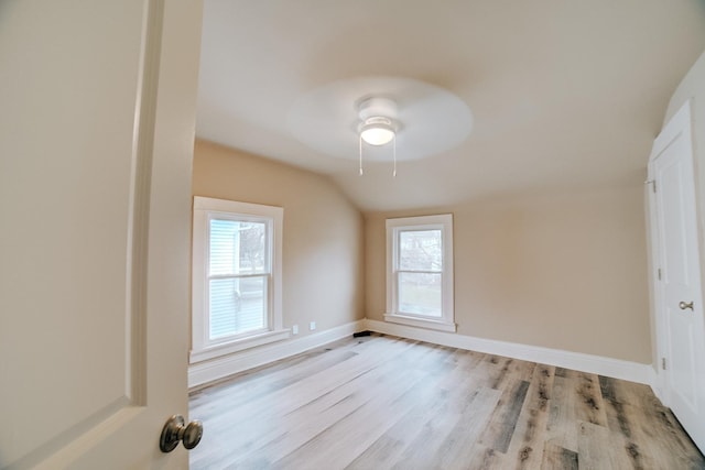 212 E Ash St, Watseka, IL 60970 - unfurnished bedroom with lofted ceiling, light wood-style floors, multiple windows, and baseboards