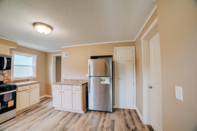 212 E Ash St, Watseka, IL 60970 - kitchen with appliances with stainless steel finishes, a textured ceiling, light wood finished floors, light countertops, and ornamental molding