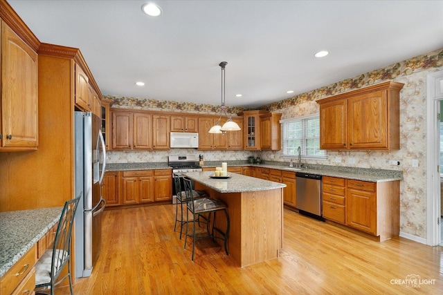 541 Clover Dr, Algonquin, IL 60102 - kitchen featuring appliances with stainless steel finishes, a sink, brown cabinets, a kitchen bar, and light wood-type flooring