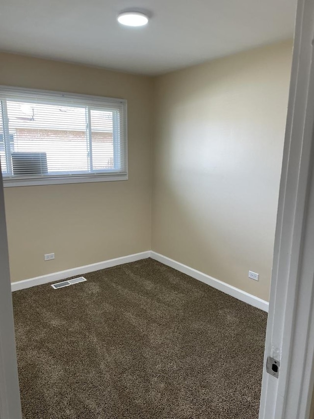 empty room featuring baseboards, dark colored carpet, and visible vents