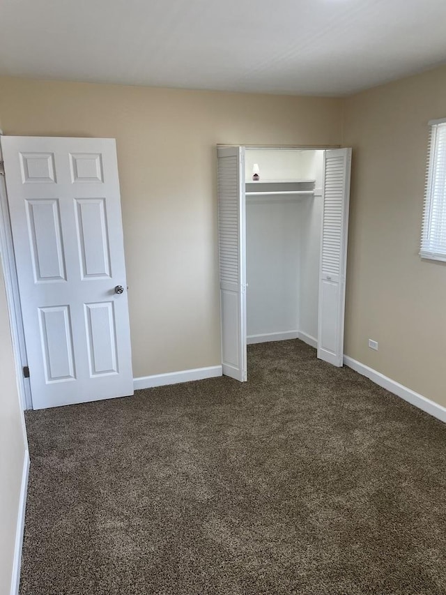unfurnished bedroom featuring dark carpet, a closet, and baseboards