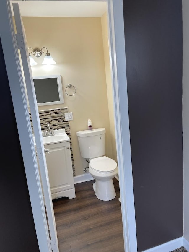 bathroom with tasteful backsplash, vanity, baseboards, toilet, and wood finished floors