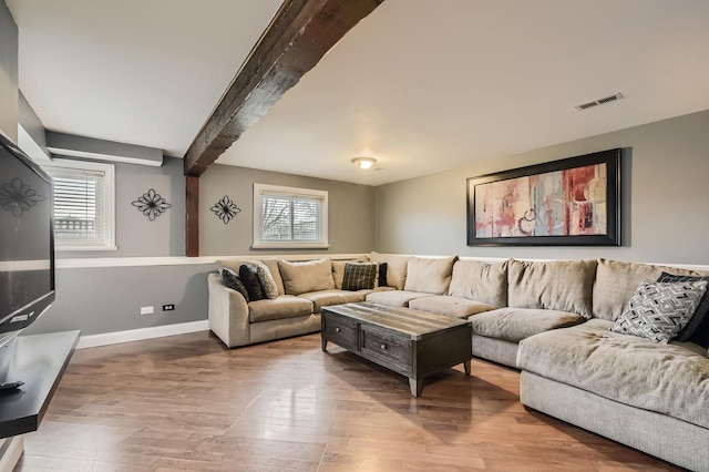 living room with visible vents, baseboards, beam ceiling, and wood finished floors