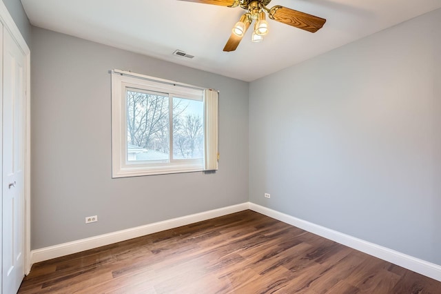 spare room with a ceiling fan, baseboards, dark wood-style floors, and visible vents