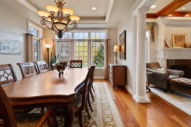 3131 Pepper Creek Bridge Pkwy, Valparaiso, IN 46385 - dining room featuring light wood-type flooring, a chandelier, ornate columns, a fireplace, and a tray ceiling