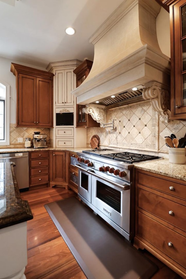 3131 Pepper Creek Bridge Pkwy, Valparaiso, IN 46385 - kitchen featuring appliances with stainless steel finishes, custom range hood, decorative backsplash, glass insert cabinets, and light stone counters