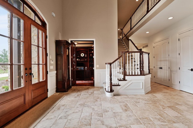 3131 Pepper Creek Bridge Pkwy, Valparaiso, IN 46385 - entryway featuring stone tile flooring, french doors, stairway, a decorative wall, and a high ceiling