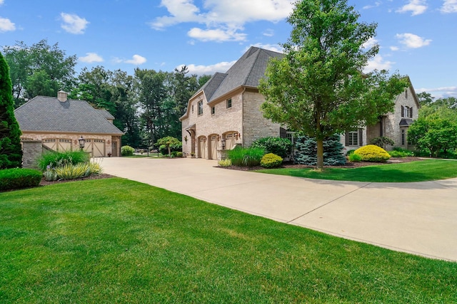 3131 Pepper Creek Bridge Pkwy, Valparaiso, IN 46385 - view of side of property featuring stone siding, a lawn, concrete driveway, and a garage
