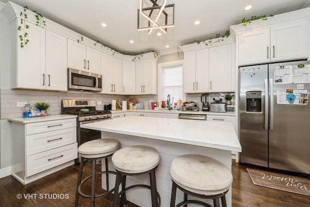7427 S Bennett Ave, Chicago, IL 60649 - kitchen with tasteful backsplash, white cabinets, dark wood-type flooring, a kitchen bar, and stainless steel appliances