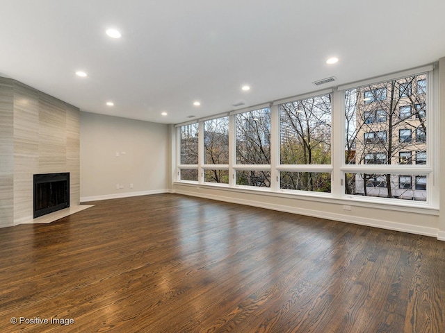 unfurnished living room featuring recessed lighting, a tile fireplace, baseboards, visible vents, and dark wood-type flooring