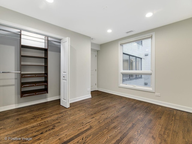 unfurnished bedroom with recessed lighting, wood finished floors, a closet, baseboards, and visible vents