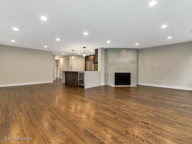 unfurnished living room with dark wood-style flooring, recessed lighting, and baseboards