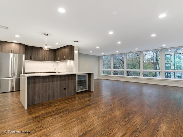 kitchen with recessed lighting, wine cooler, dark brown cabinetry, light countertops, and stainless steel refrigerator