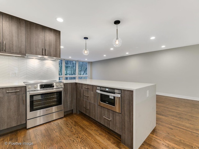 kitchen with dark wood finished floors, dark brown cabinetry, a peninsula, and appliances with stainless steel finishes