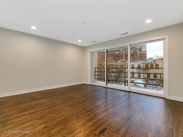 spare room featuring wood finished floors, visible vents, recessed lighting, and baseboards