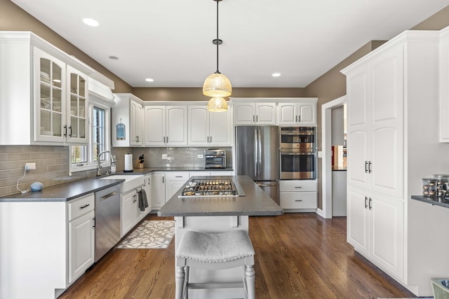 kitchen featuring glass insert cabinets, dark wood-style floors, white cabinetry, stainless steel appliances, and a sink