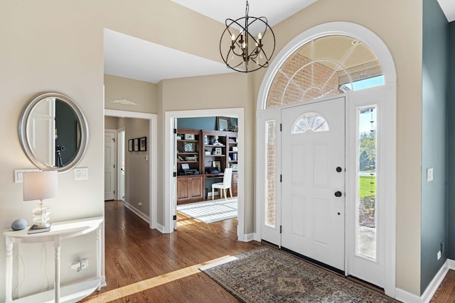 foyer featuring wood finished floors, an inviting chandelier, and baseboards