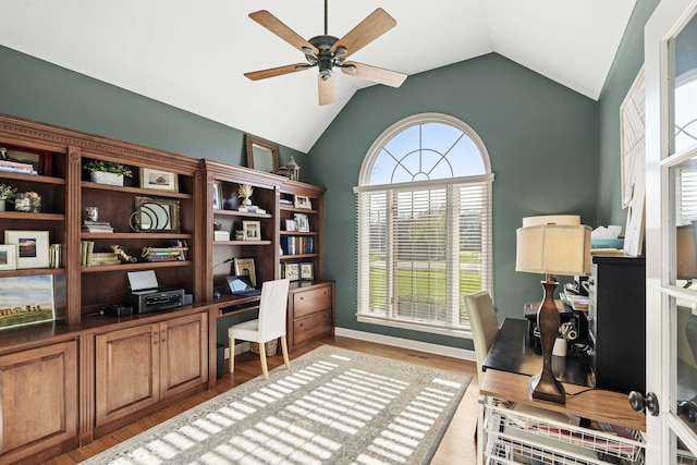 office with light wood-style flooring, a ceiling fan, vaulted ceiling, and baseboards
