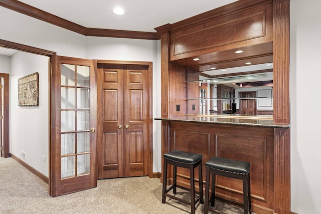 bar featuring a bar, carpet flooring, baseboards, and ornamental molding