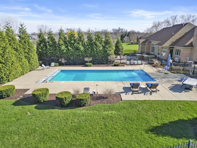 community pool featuring a patio area, fence, and a lawn