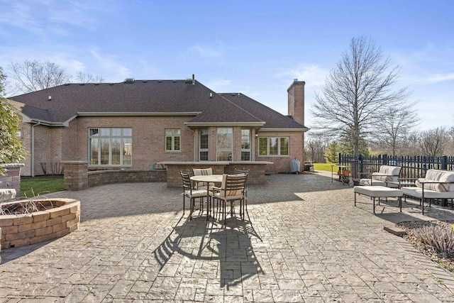 view of patio with outdoor dry bar, fence, and a fire pit