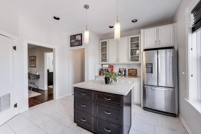 834 W Belle Plaine Ave Unit 3W, Chicago, IL 60613 - kitchen with visible vents, hanging light fixtures, stainless steel fridge, light countertops, and decorative backsplash