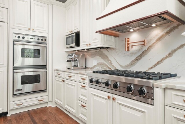 96 S Wynstone Dr, North Barrington, IL 60010 - kitchen featuring appliances with stainless steel finishes, custom range hood, white cabinetry, dark wood-style floors, and light stone countertops