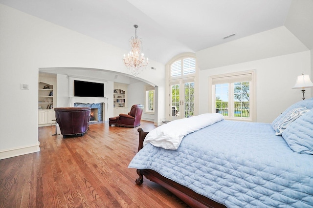 96 S Wynstone Dr, North Barrington, IL 60010 - bedroom with wood finished floors, a chandelier, a fireplace with flush hearth, high vaulted ceiling, and arched walkways