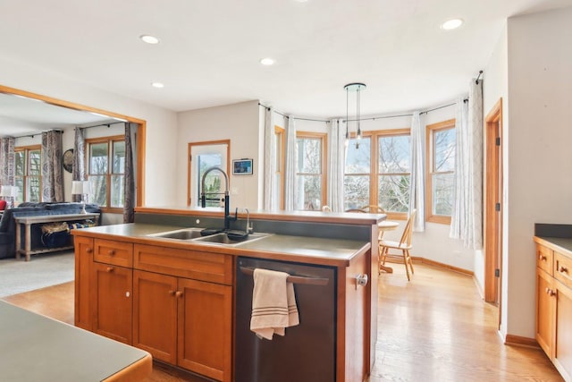kitchen with brown cabinetry, pendant lighting, stainless steel dishwasher, a sink, and recessed lighting