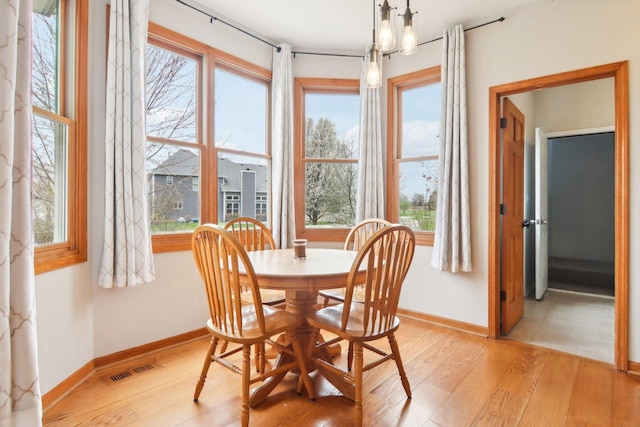 dining space with baseboards, light wood-style flooring, and visible vents