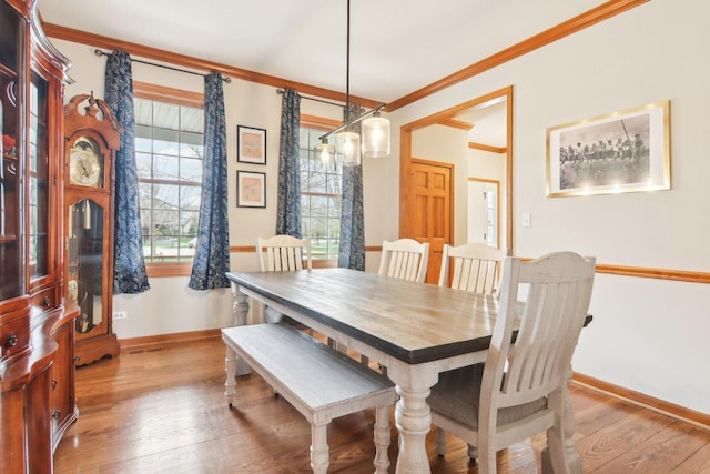 dining space featuring crown molding, baseboards, and light wood-style floors