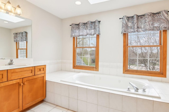 bathroom featuring vanity, a bath, a healthy amount of sunlight, and a skylight