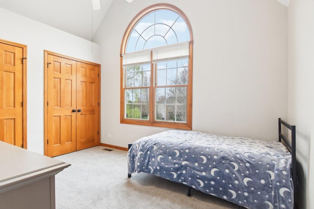 carpeted bedroom with baseboards, vaulted ceiling, visible vents, and a closet
