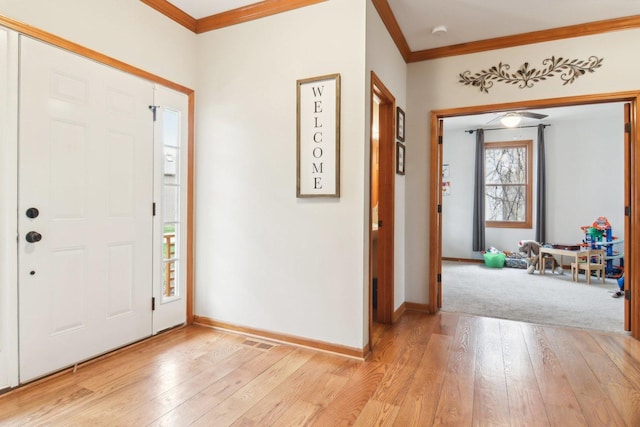 foyer featuring baseboards, ornamental molding, light wood finished floors, and visible vents