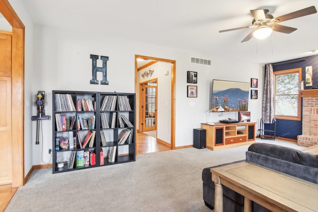 living area featuring carpet floors, baseboards, a ceiling fan, and visible vents