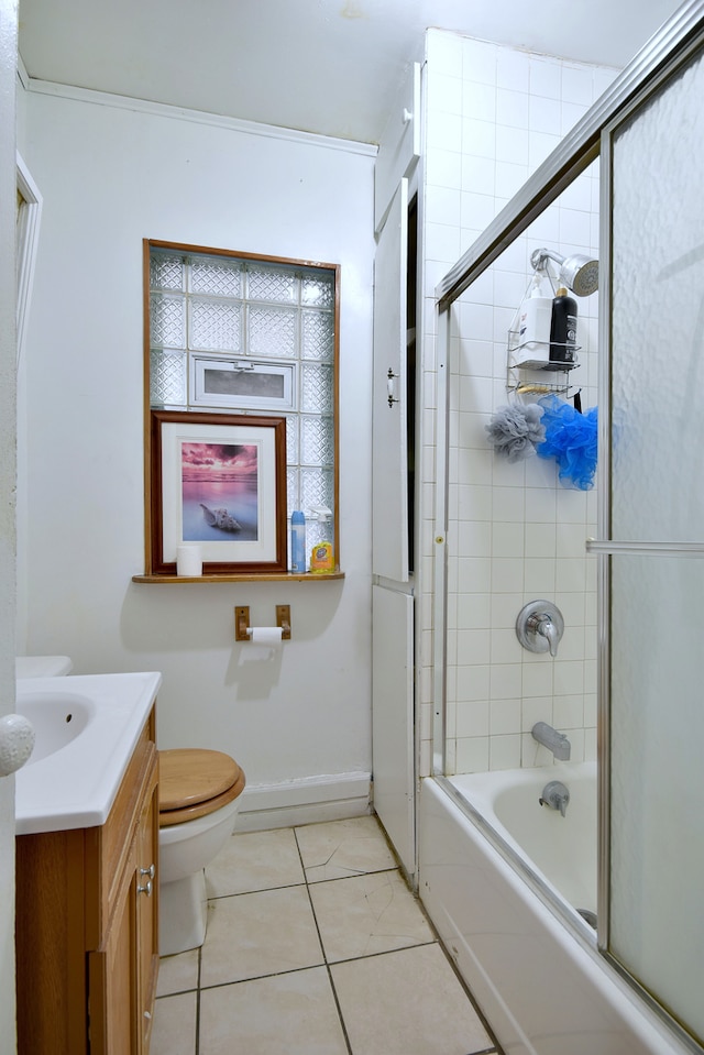 bathroom with baseboards, bath / shower combo with glass door, toilet, vanity, and tile patterned floors