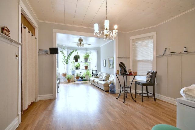 interior space with light wood finished floors, ceiling fan with notable chandelier, and crown molding