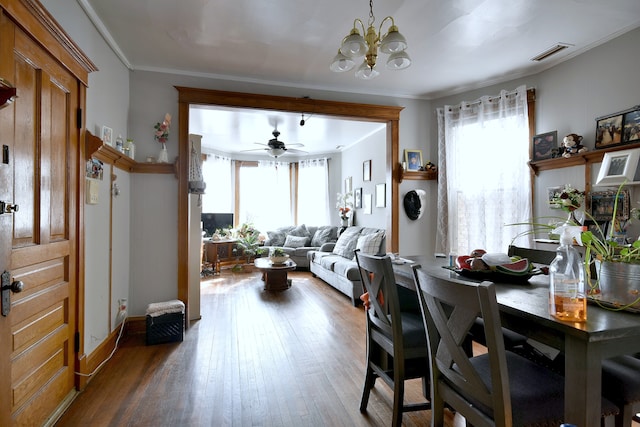 dining room featuring crown molding, ceiling fan with notable chandelier, visible vents, wood finished floors, and baseboards