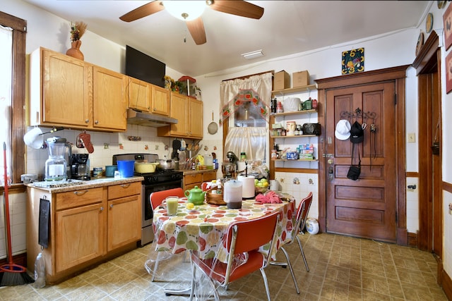 kitchen with stainless steel range with gas cooktop, tasteful backsplash, a ceiling fan, under cabinet range hood, and light countertops