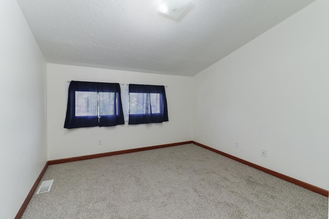 carpeted empty room featuring a textured ceiling, visible vents, and baseboards