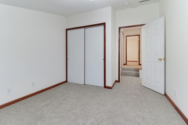 unfurnished bedroom featuring light colored carpet, baseboards, and a closet