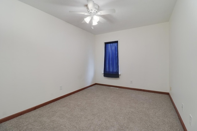 carpeted spare room featuring baseboards and a ceiling fan