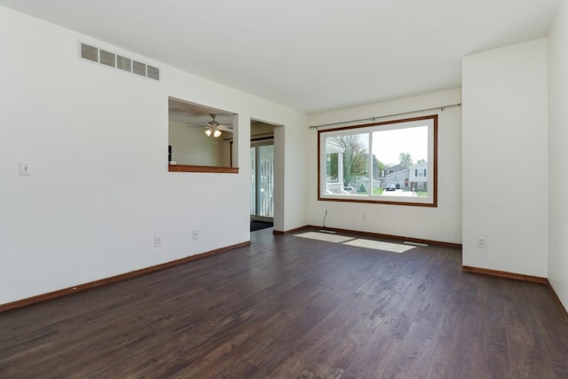 empty room featuring baseboards, a ceiling fan, dark wood-style floors, and visible vents