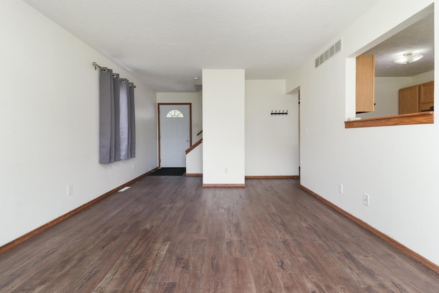 interior space with baseboards, visible vents, and dark wood finished floors
