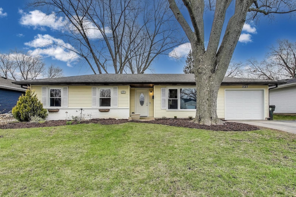 ranch-style home with an attached garage, driveway, and a front lawn