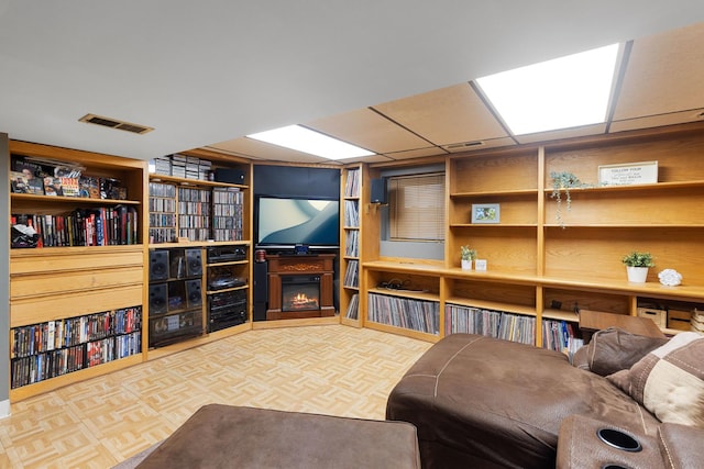 living area featuring a warm lit fireplace and visible vents