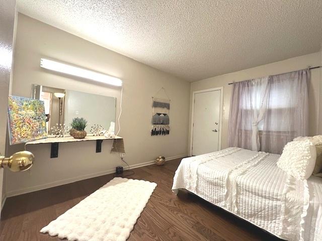 bedroom featuring baseboards, wood finished floors, and a textured ceiling