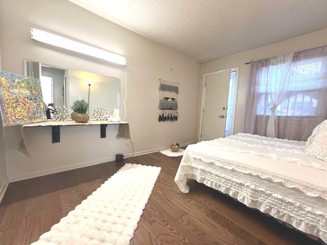 bedroom featuring a textured ceiling, baseboards, and wood finished floors