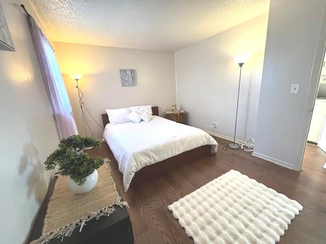bedroom featuring baseboards, wood finished floors, and a textured ceiling